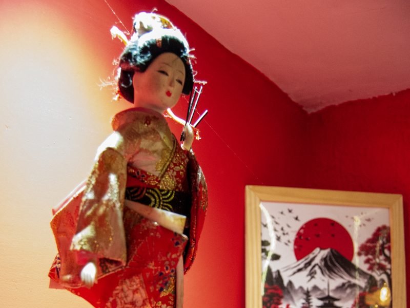 Boneca decorativa com quimono vermelho e quadro com paisagem japonesa