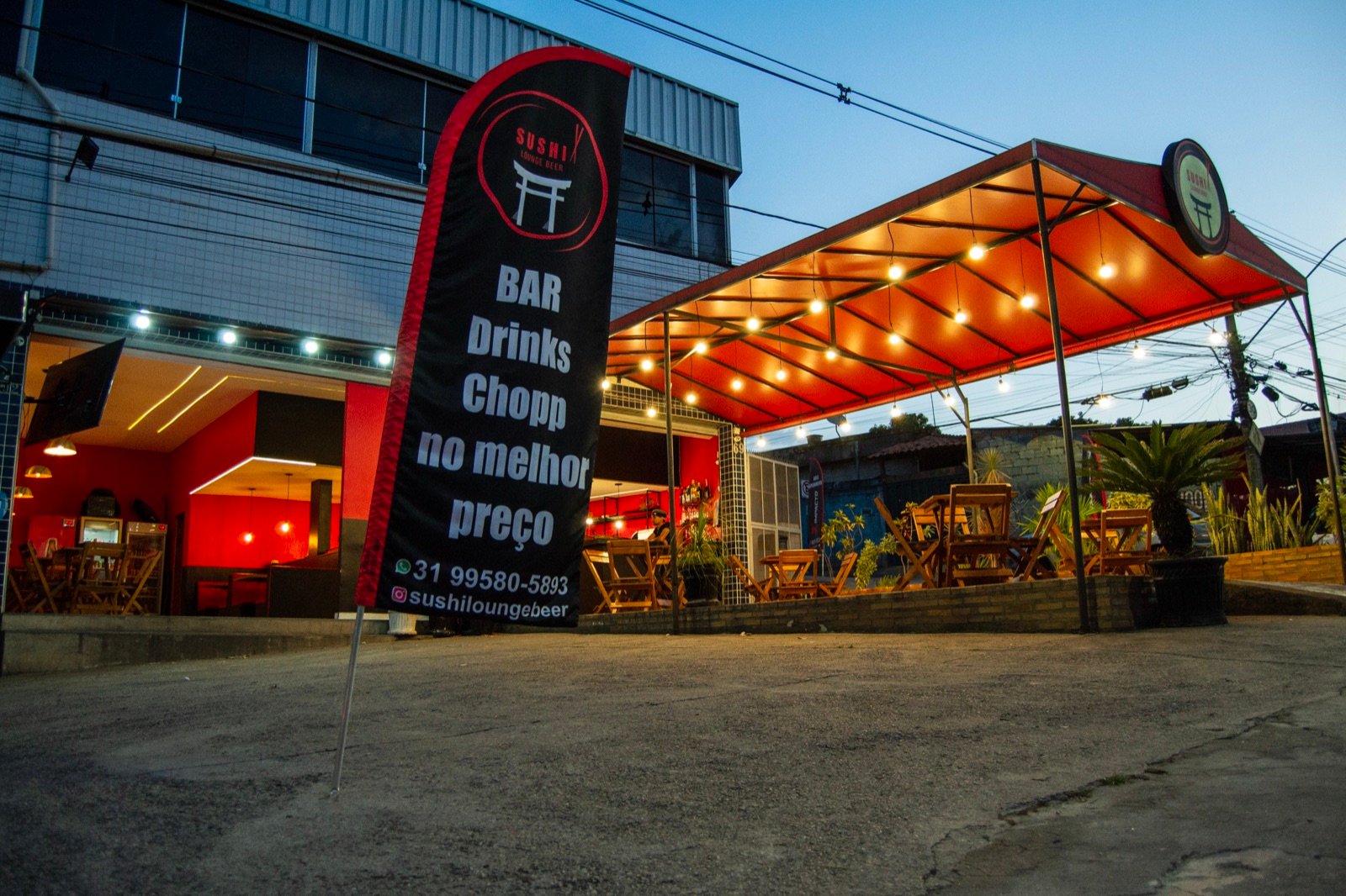 Fachada do Sushi Lounge Beer no Serra Verde, com mesas na área externa iluminada